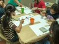 Participantes del taller pintando con gomitas elásticas amarradas a bloques de madera