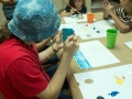 Participantes del taller aprendiendo a hacer obras con gomitas elásticas amarradas a bloques de madera