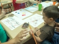 Participantes del taller aprendiendo a hacer obras con gomitas elásticas amarradas a bloques de madera