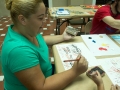 Participantes del taller aprendiendo a hacer obras con gomitas elásticas amarradas a bloques de madera