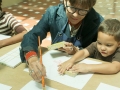 Participantes del taller aprendiendo a hacer obras con gomitas elásticas amarradas a bloques de madera